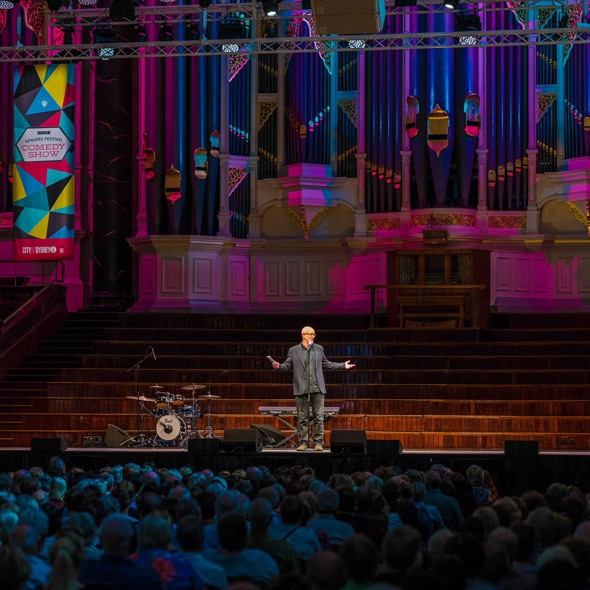 A comedian performing to a packed audience at the NSW Seniors Festival Comedy Show, Sydney Town Hall